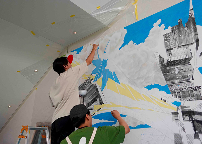 Photo of Mr. Ujitoshi Akasa and his friend creating the mural