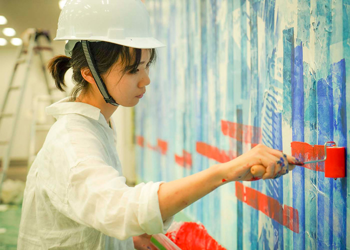 Photo of Ms. Kotori Nakamura painting the mural