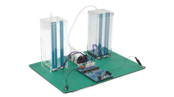 Angled view of the capacitive touch liquid level indicator reference design with two transparent tanks, connecting tubes, sensors, and a CPU board and control board.