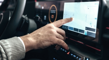 Automotive Infotainment Screen Finger touching a car's infotainment screen to navigate maps.
