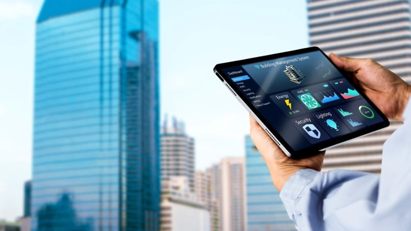 Engineer hands using digital tablet with building management software on blurred modern office building as background