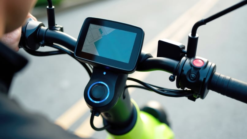 Close‑up of a handlebar‑mounted TFT display on a two‑wheeler, showing navigation and ride information with integrated control buttons.